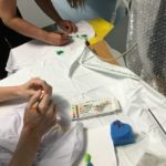 Two students painting and drawing on their t-shirts