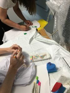 Two students painting and drawing on their t-shirts