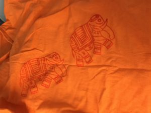 Red elephants stamped on an orange t-shirt