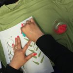 Student using flower stencil on their t-shirt