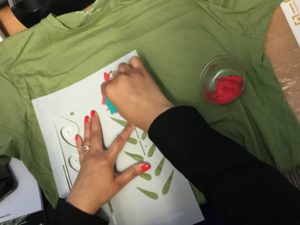 Student using flower stencil on their t-shirt